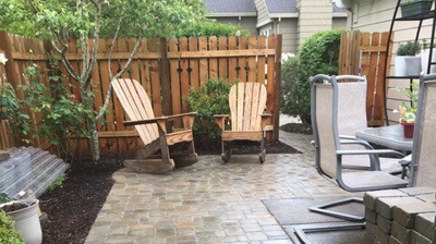 A brick walkway leading up to a corner with two wooden chairs Photo