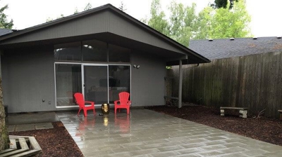 Grey brick patio hardscaping with two red chairs in a backyard Photo