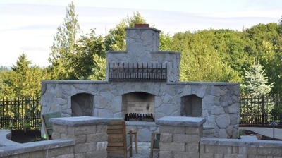 An elaborate brick outdoor fireplace with two smaller brick walls in front of it Photo