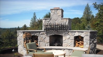 An outdoor brick fireplace with patio furniture in front of it Photo